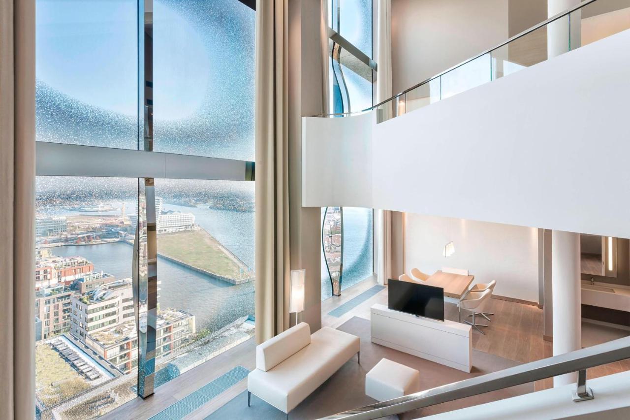 더 웨스틴 함부르크 함브루크 외부 사진 The photo showcases a modern, stylish interior of a multi-level living space. It features large, floor-to-ceiling windows that provide a panoramic view of the surrounding landscape and water. The decor is minimalist, with a predominantly white color 
